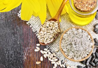 Sunflower seeds, oil, and powder on a wooden surface with a yellow sunflower, resembling what is sunflower lecithn.