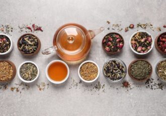 Glass teapot with herbal blends in small bowls, showcasing various types of tea for lymphatic system support.