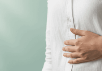 Close-up of a person's hand on their upper right abdomen (gallbladder area) against a mint green background.